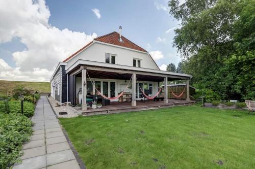 a white house with a porch and a yard at Ruime boerderij met haard, pooltafel en veranda in Goilberdingen