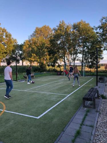 a group of people playing tennis on a tennis court at Ruime boerderij met haard, pooltafel en veranda in Goilberdingen
