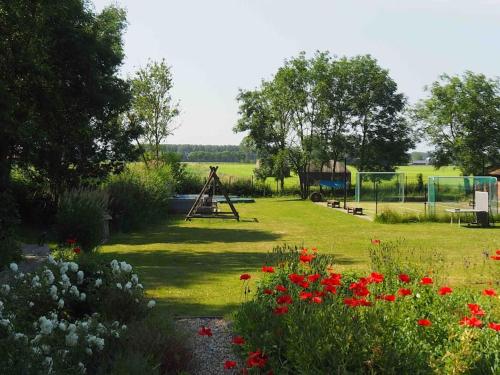 a garden with flowers and a swing set in the background at Ruime boerderij met haard, pooltafel en veranda in Goilberdingen