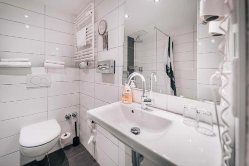 a white bathroom with a sink and a toilet at Hotel International am Theater in Münster