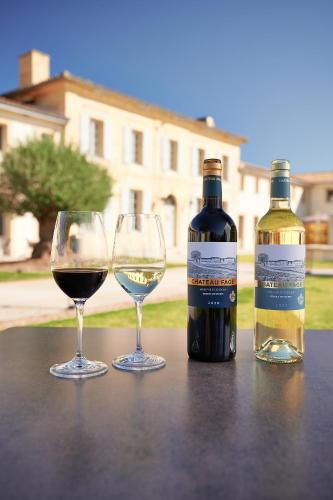 two glasses and a bottle of wine on a table at Château Fage La Maison des Vignes - Saint-Émilion in Arveyres