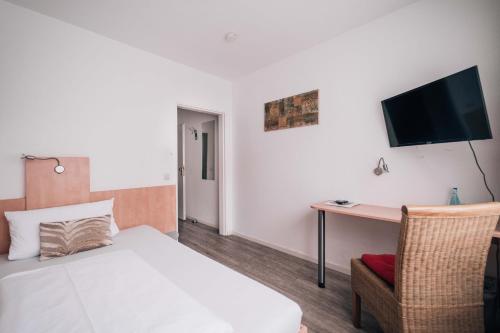 a bedroom with a bed and a desk and a tv at Hotel International am Theater in Münster
