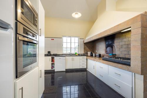 a kitchen with white cabinets and a black floor at A Casa do Lagar in São Jorge