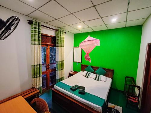 a green bedroom with a bed and a green wall at Lalanga Homestay in Kandy