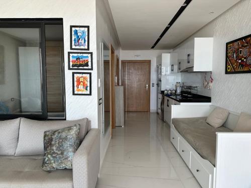 La perle de Mehdia sea view appartement في Mehdiya-Plage: غرفة معيشة مع أريكة ومطبخ