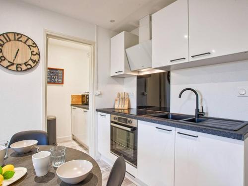 une cuisine avec des placards blancs et une table avec une horloge dans l'établissement Évasion lumineuse à Cabourg avec parking, cuisine équipée et proche bord de mer - FR-1-788-35, à Cabourg
