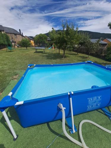 a blue pool with a hose in a yard at Casa Rural Abuelo Jose in Robledo de las Traviesas