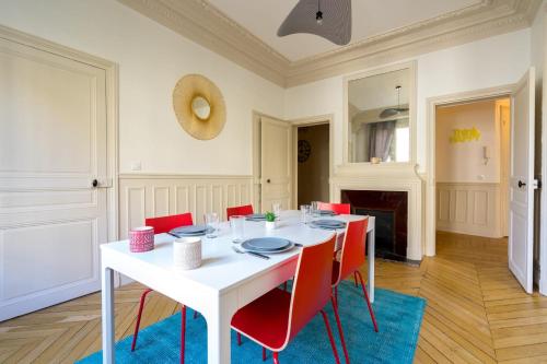 une salle à manger avec une table blanche et des chaises rouges dans l'établissement Apartment 3BR - 10P - Passy - Eiffel Tower, à Paris
