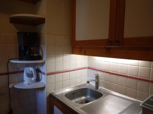 - une petite cuisine avec un évier et un miroir dans l'établissement Appartement ski aux pieds avec balcon et WIFI - FR-1-181-2838, à La Plagne Tarentaise