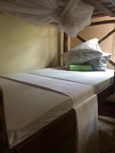 a bed with white sheets and pillows on it at Janibichi Adventures hostel in Moshi