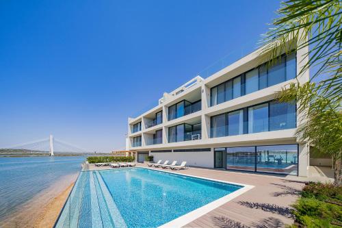 a large building with a swimming pool next to the water at Portimão Ocean Breeze With Pool by Homing in Lagoa