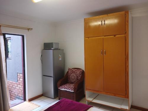 a room with a cabinet and a chair and a refrigerator at Kadichueni Guest House in Zeerust