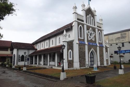 a large white building with a tower on a street at Sheru Guest in Matara