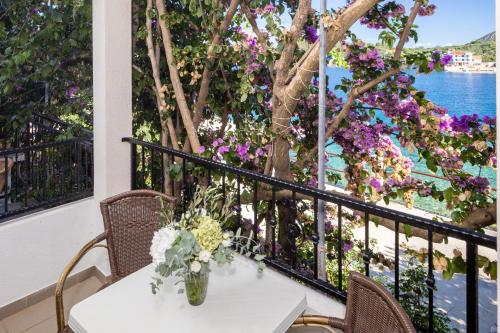 a table with a vase of flowers on a balcony at Apartmani Nikola in Zastražišće