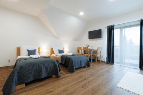 a room with two beds and a table with a television at RHOLL Pension & Restaurant in Hámry