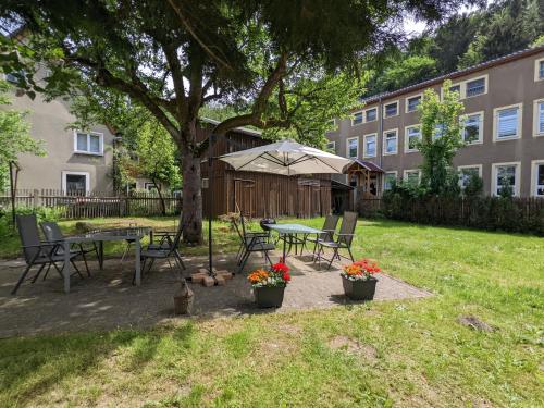 a patio with a table and chairs under a tree at H2 - Urlaubsmagie - Garten, Pool, Terrasse, Grill in Sebnitz