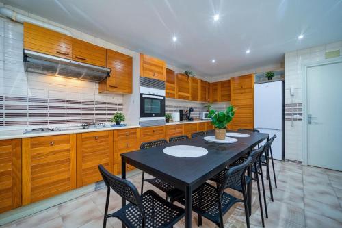 a kitchen with wooden cabinets and a black table and chairs at P CasaCafe Madrid Calle Carlos Dubois 3 in Madrid