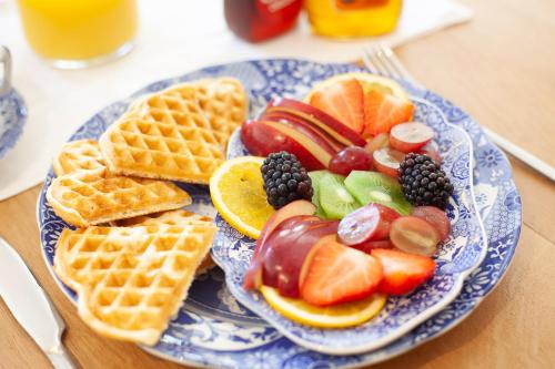 a blue and white plate of food with fruit and waffles at The Rose and Thistle Alwinton in Morpeth
