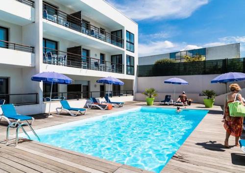 a woman standing next to a swimming pool next to a building at Caporizon-l'Archipel-T1-Piscine-centre ville-Terrasse in La Rochelle