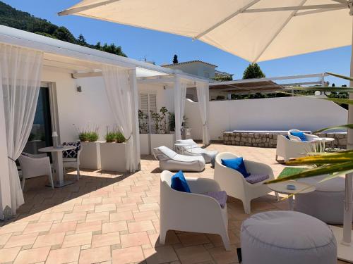 a patio with white chairs and tables and an umbrella at Bettola del Re home boutique b&b in Anacapri