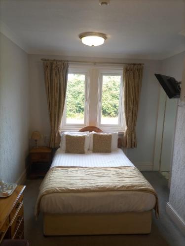 a bedroom with a large bed with two windows at The Carre Arms Hotel & Restaurant in Sleaford