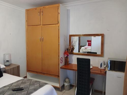 a bedroom with a desk and a cabinet and a mirror at Kadichueni Guest House in Zeerust