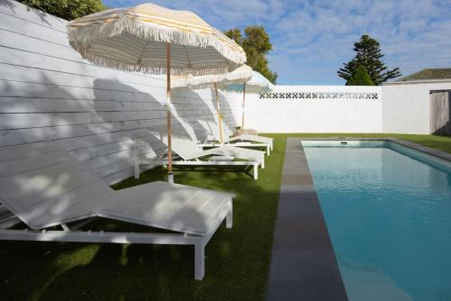 a group of white chairs and an umbrella next to a pool at Warm Heated Pool All Year - Palm Springs in Torquay