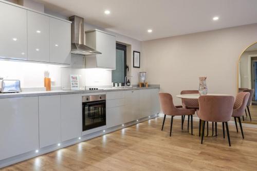 a kitchen with white cabinets and a table and chairs at Boutique City Center Apartment in Belfast