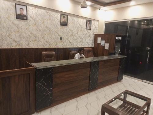 a woman sitting at a counter in a lobby at Airport Guest House - JIA in Karachi