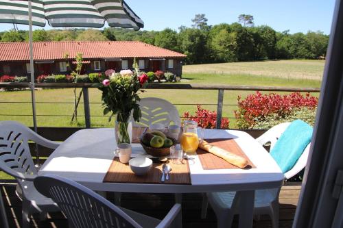 une table blanche avec un vase de fleurs sur un balcon dans l'établissement Olydea la Chalosse - Cassen, à Cassen