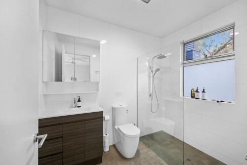 a white bathroom with a toilet and a shower at Aireys Bush Retreat in Aireys Inlet