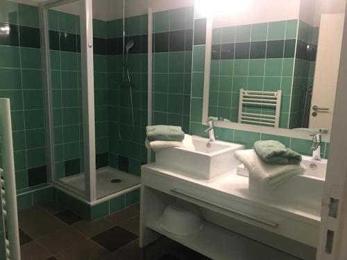 La salle de bains est pourvue de carrelage vert, d'un lavabo et d'une douche. dans l'établissement Appt à Baden au château de Kergonano, à Mériadec