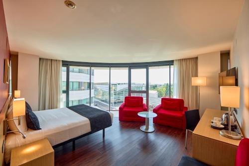 pokój hotelowy z łóżkiem i 2 czerwonymi krzesłami w obiekcie Civis Luz Castellón 4*S w mieście Castellón de la Plana