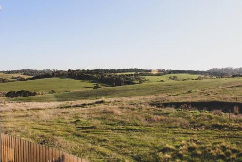 a green field with a fence in the foreground at ALMA - sun filled stylish beach house in Torquay