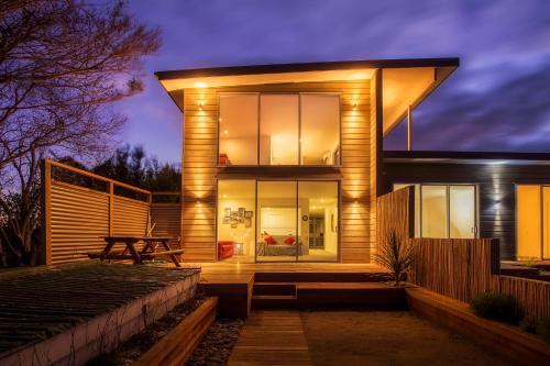 a house with glass doors and a table in front of it at Mapua Wharfside Apartments in Mapua