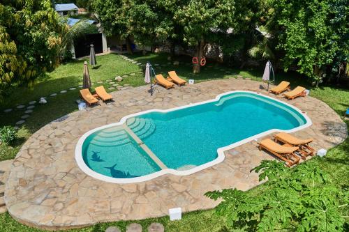 an overhead view of a swimming pool with chairs and umbrellas at SHIMBA SPRINGS MBUYU. ( Malindi) in Malindi
