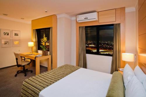 a hotel room with a bed and a desk and a window at h604 - Flat Aeroporto Congonhas in São Paulo
