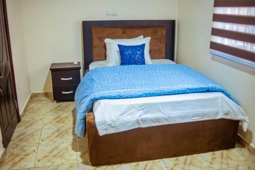 a bedroom with a bed with a blue comforter at Vitoria Apartment 2 in Gidan Nbora