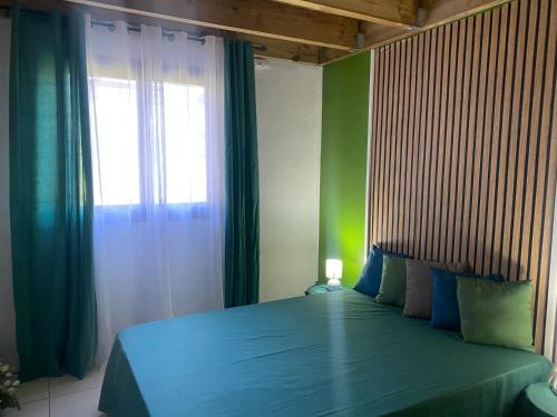 a bedroom with a blue bed with a window at L'Endémik Kréol in Saint-André