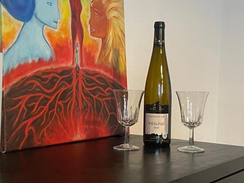 a bottle of wine and two glasses on a table at Chambre Kayalvizhi in Vendenheim