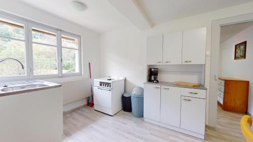 une cuisine avec des armoires blanches, un évier et une fenêtre dans l'établissement Le Bois Dormant 1, à Rimbach-près-Masevaux