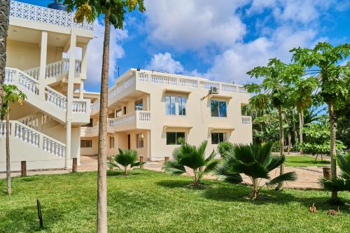 a large white building with palm trees in front of it at SHIMBA SPRINGS MBUYU. ( Malindi) in Malindi