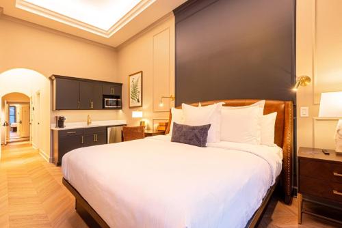 a bedroom with a large white bed and a kitchen at Sinclair Suites - Stylish Retro Boutique Hotel in West Dundee