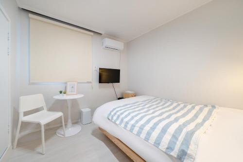 a white bedroom with a bed and a chair and a window at Mutal Stay in Seoul