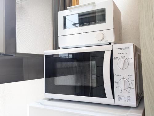 a white microwave oven sitting on top of a counter at 鶴の宿 那覇-国際通りまで950mの便利な立地-1棟貸切 in Naha