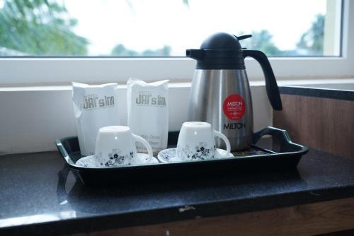 a tray with a tea kettle and cups on a counter at Hotel Jai's Inn in Thanjāvūr
