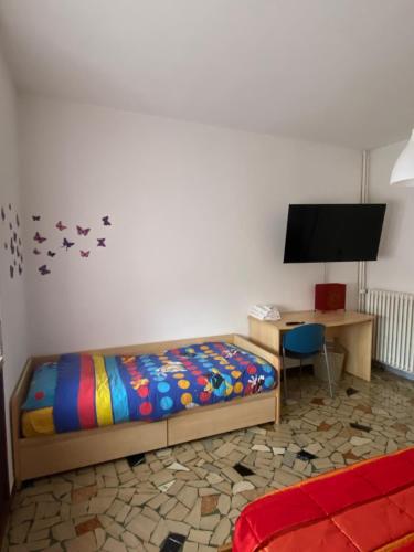 a bedroom with a bed and a desk and a tv at Appartamento " Le Farfalle " in Santorso