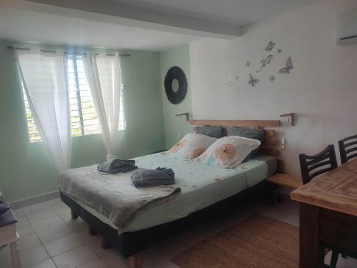 a bedroom with a bed in a room with a table at La passiflore in Le Gosier