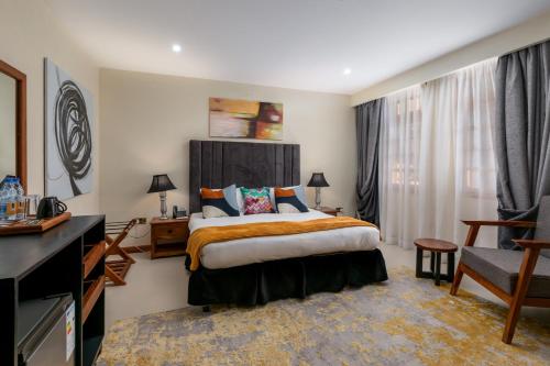 a bedroom with a bed and a desk and a chair at The Emin Pasha Hotel & Spa Kampala in Kampala