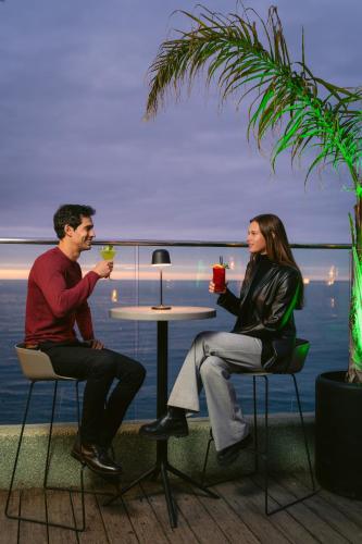 a man and woman sitting at a table with drinks at Pullman Vina del Mar San Martin in Viña del Mar
